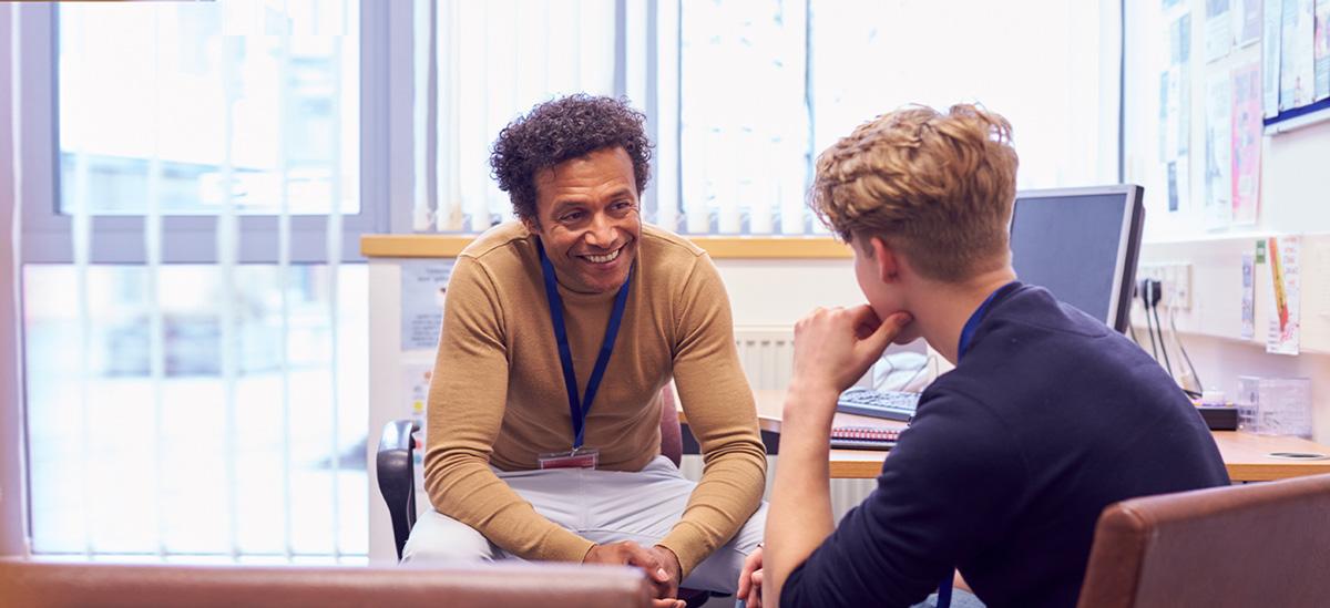 An advisor speaks to a student in his office